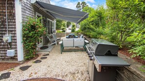 A backyard with a barbecue grill, outdoor seating, and a covered patio area. - South Chatham Gem - .4 Mile to Pleasant Street Beach (South Chatham)
