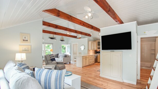 A spacious living area with a sofa, a television, and a kitchen in the background. - South Chatham Gem - .4 Mile to Pleasant Street Beach (South Chatham)