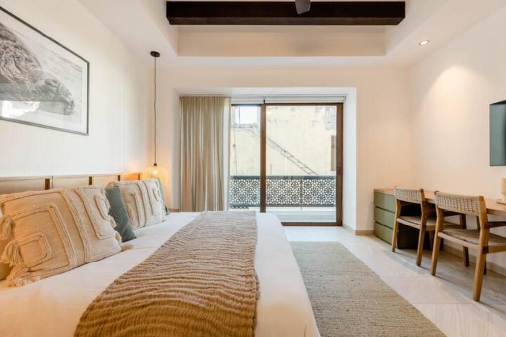 Une chambre dotée d’un grand lit, d’un bureau et donnant sur un balcon extérieur par le biais d’une porte coulissante.