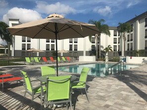 Ein Poolbereich mit Pool, Liegestühlen und einem Tisch mit Stühlen.