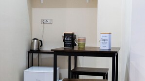 Ett litet kök med en kaffebryggare, en behållare för socker och en liten hylla med dekorativa föremål.