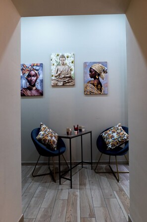 A corner room with two blue chairs, a small table, and three artworks on the wall. - Boutique Rooms in the Heart of Naples' Historic Center (Napoli)