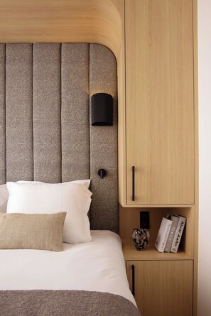 Une chambre à coucher comprenant un lit, une tête de lit, une table de chevet et une commode.