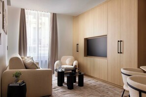 Un salon moderne comprenant un canapé, des fauteuils, une table basse et un téléviseur à écran plat fixé à un mur en bois.