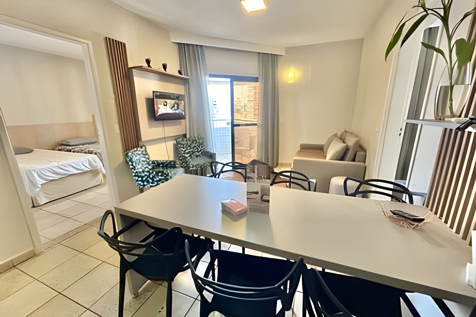 A modern, well-lit room with a dining table, chairs, a sofa, and a bed.