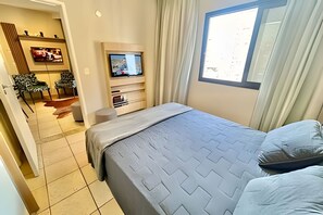 Ein Hotelzimmer mit Bett, Fernseher, einer Sitzecke mit Stühlen und einem Fenster.