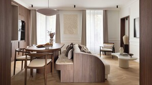 A modern living room with a curved sofa, a dining table with chairs, and a large window. - Luxury Apartment / AC - 4br/ 8P - Bastille (Paris)