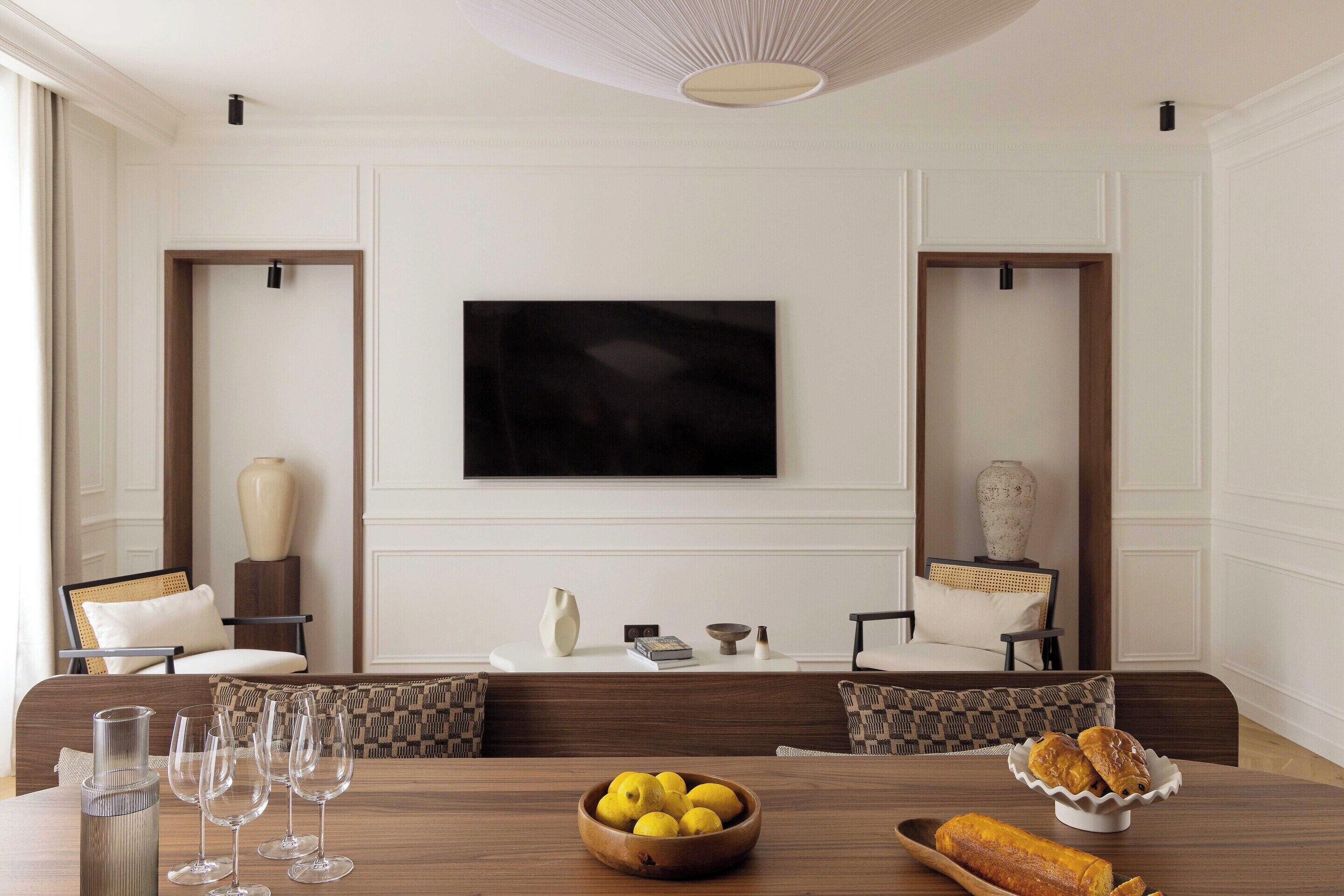 A dining area with a wooden table, chairs, a bowl of lemons, and a loaf of bread.