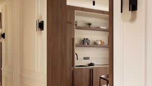 A hallway with a wooden door frame, a white wall with a light switch, and a wooden floor. - Luxury Apartment / AC - 4br/ 8P - Bastille (Paris)