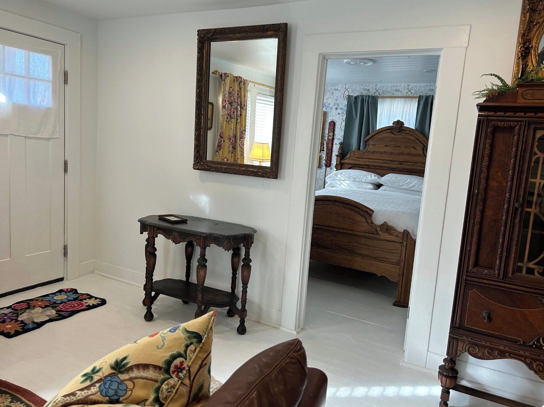 A bedroom with a wooden bed, a nightstand, a mirror, and a door leading to another room.