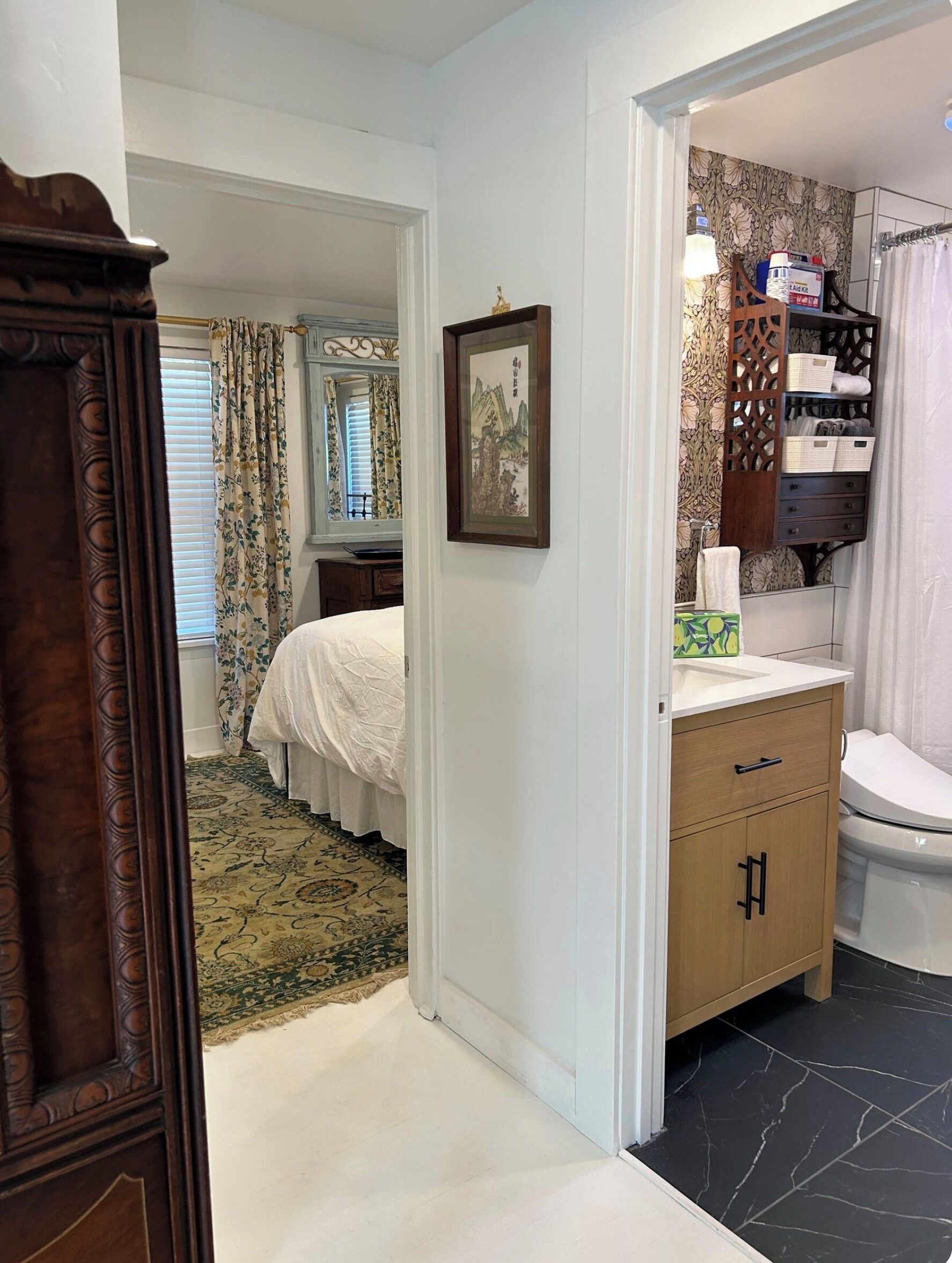 Um quarto com uma cama, cômoda de madeira e banheiro com vaso sanitário e prateleiras.