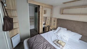 Et hotelværelse med en seng, et garderobeskab, et natbord og en taske hængende.