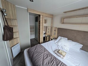 Ein Hotelzimmer mit Bett, Schrank, Nachttisch und einer aufhängbaren Tasche.