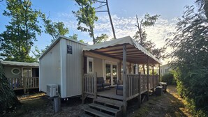 En campingvogn med veranda, udendørs siddepladser og en lille terrasse.