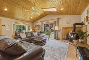 A cozy living room with leather sofas, a fireplace, and a ceiling fan. - The Rabbit Hole - Sauna. Soak. Repeat. (South Lake Tahoe)