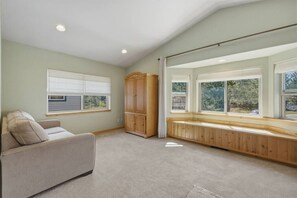 A room with a built-in bench along a large window, a sofa, and a wooden cabinet. - The Rabbit Hole - Sauna. Soak. Repeat. (South Lake Tahoe)