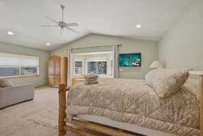 Een slaapkamer met een bed, een plafondventilator, een raam en een televisie.