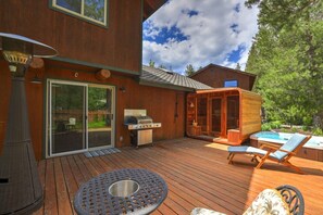 Terraza de madera con parrilla, mobiliario exterior y un jacuzzi.
