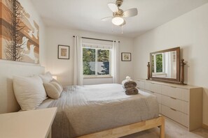A bedroom with a bed, a bedside table, a dresser, a ceiling fan, and a window with curtains. - The Rabbit Hole - Sauna. Soak. Repeat. (South Lake Tahoe)