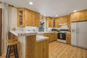 Una cocina con armarios de madera, una isla central, un refrigerador y un microondas.