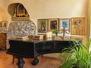 A room with a piano, books, a vase with flowers, and framed artwork on the wall. - Le Stanze degli Artisti by Case al Lago (Monzambano)