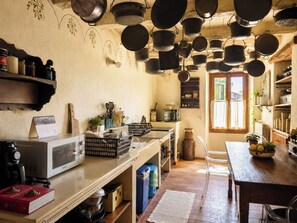 A rustic kitchen with hanging pots, a microwave, and a calendar on the counter. - Le Stanze degli Artisti by Case al Lago (Monzambano)