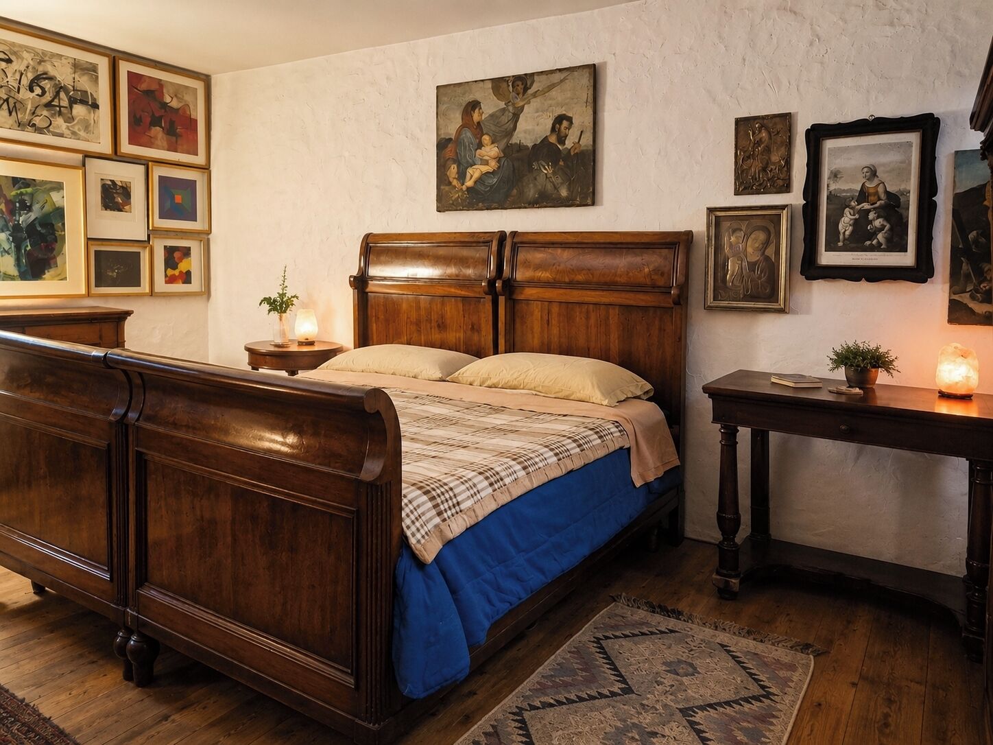 A bedroom with a wooden four-poster bed, a nightstand with a lamp, and a wall adorned with framed artwork.