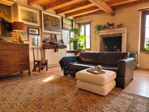 A cozy living room with a fireplace, leather sofa, and a patterned rug. - Le Stanze degli Artisti by Case al Lago (Monzambano)