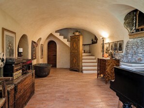 Ein geräumiges Zimmer mit einem Klavier, einem großen Holzschrank und einer Treppe, die zu einer oberen Ebene führt.