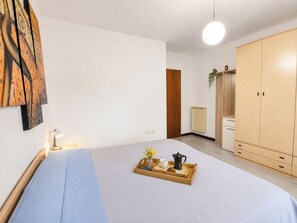 A bedroom with a bed, a wooden wardrobe, a radiator, and a wall-mounted artwork. - Iorek House by Case al Lago (Sirmione)