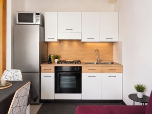 A compact kitchen with a microwave, stove, oven, and white cabinets. - Iorek House by Case al Lago (Sirmione)