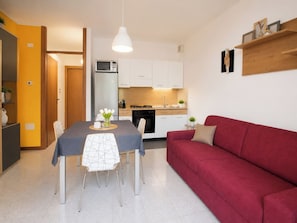 A compact living space with a dining area, kitchenette, and a red sofa. - Iorek House by Case al Lago (Sirmione)