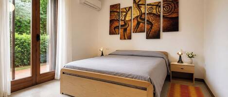 A bedroom with a bed, a nightstand, a lamp, and a wall with abstract art.
