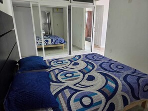 Ein Schlafzimmer mit einem Bett, einem Fenster und einer Tür zu einem anderen Raum.