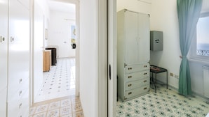 Ein Zimmer mit Schrank, Tisch und einem fenster mit Vorhang.