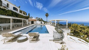 Ein Poolbereich mit Liegestühlen, einer Pergola und Meerblick.
