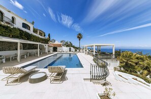 Ein Poolbereich mit Liegestühlen, einer Pergola und Meerblick.