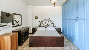 Ein Schlafzimmer mit einem hölzernen Bett, einem Schminktisch, einem Kleiderschrank, einem Fernseher und einem Spiegel.
