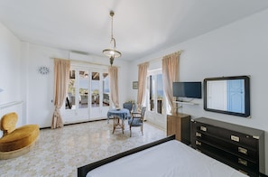 Ein Hotelzimmer mit Bett, Schreibtisch, Stuhl, Fernseher und Blick ins Freie.