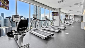 Ein Fitnessstudio mit Laufbändern, Fahrrädern und Blick auf die Stadt.