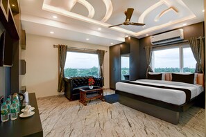 A modern hotel room with a bed, a sofa, a coffee table, and a view of the city.