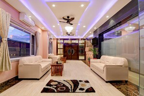 A hotel lobby with a ceiling fan, recessed lighting, a chandelier, and a large mirror.