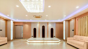 Eine großzügige Hotelhalle mit einer zentralen Sitzecke, eingelassener Beleuchtung und einem großen Kronleuchter.
