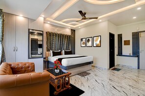 A modern hotel room with a bed, a seating area, a desk, and a bathroom.