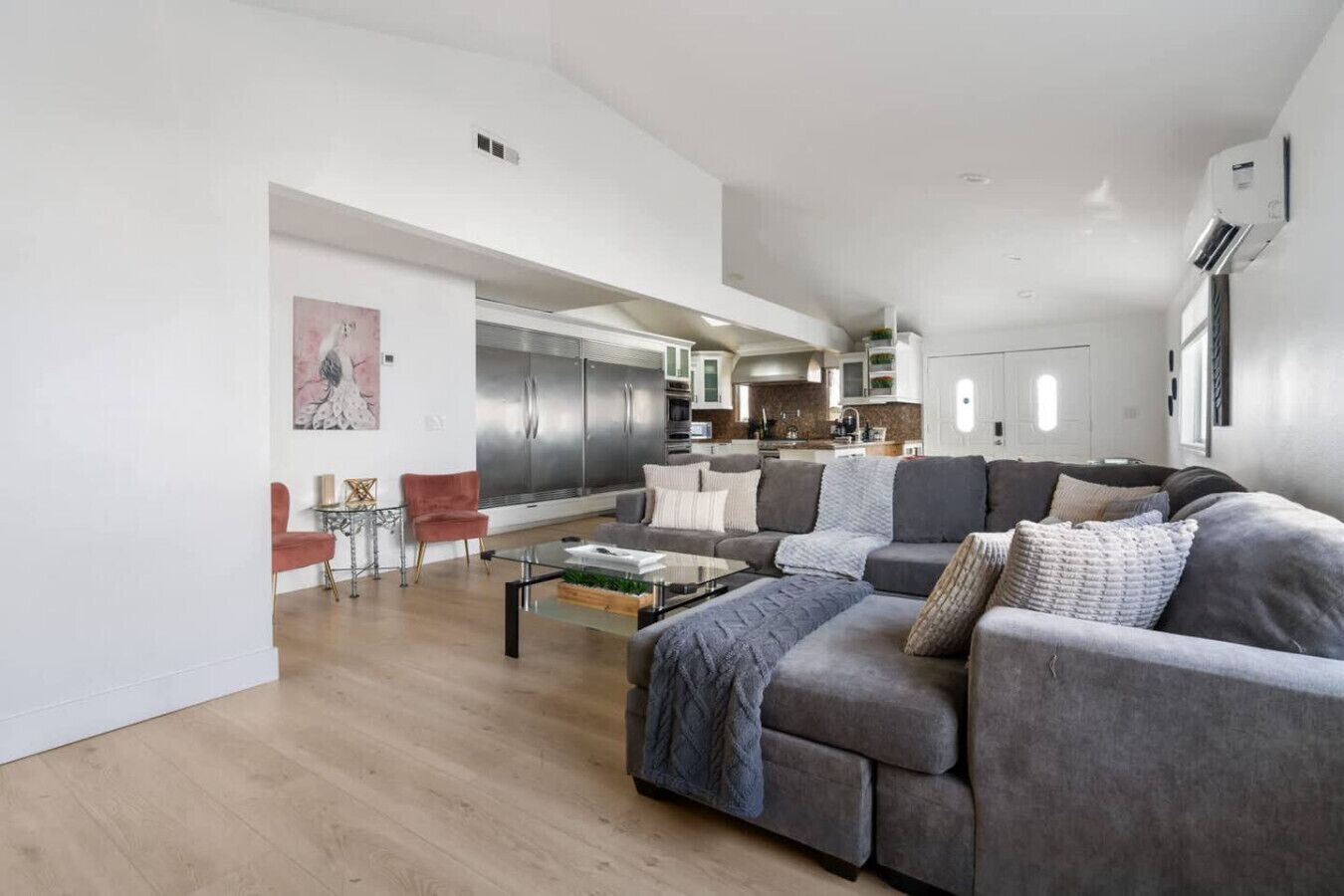 Una sala moderna con un sofá modular, una mesa de centro de vidrio y una silla roja.