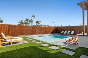 A backyard with a swimming pool, wooden deck, and lounge chairs. - Family Pool House Oasis (National City)
