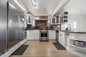 A modern kitchen with stainless steel appliances, white cabinetry, and a granite countertop. - Family Pool House Oasis (National City)