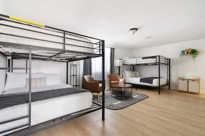 A modern hotel room with bunk beds, a desk, a chair, and a small table. - Family Pool House Oasis (National City)