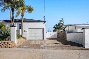 A residential property with a garage, a fenced yard, and palm trees. - Family Pool House Oasis (National City)
