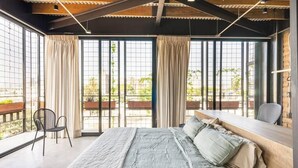 A bedroom with a large bed, a desk, and a view of the outdoors through large windows. - Argentina by Pardela (Guadalajara)